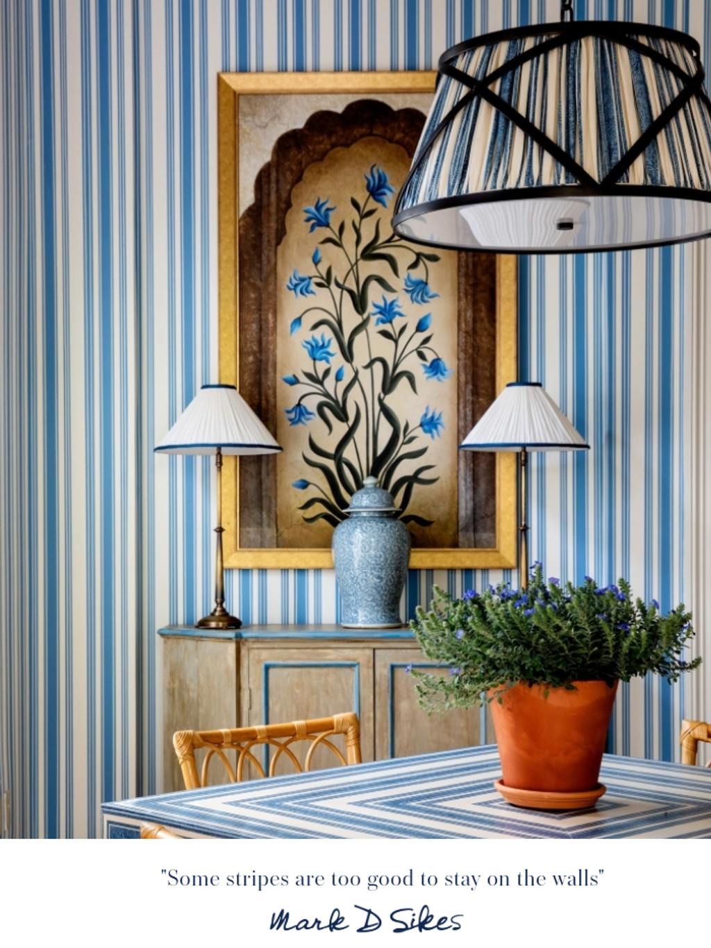 A blue and white striped dining room featuring striped wallpaper, a matching patterned table, botanical art, and pendant light.
