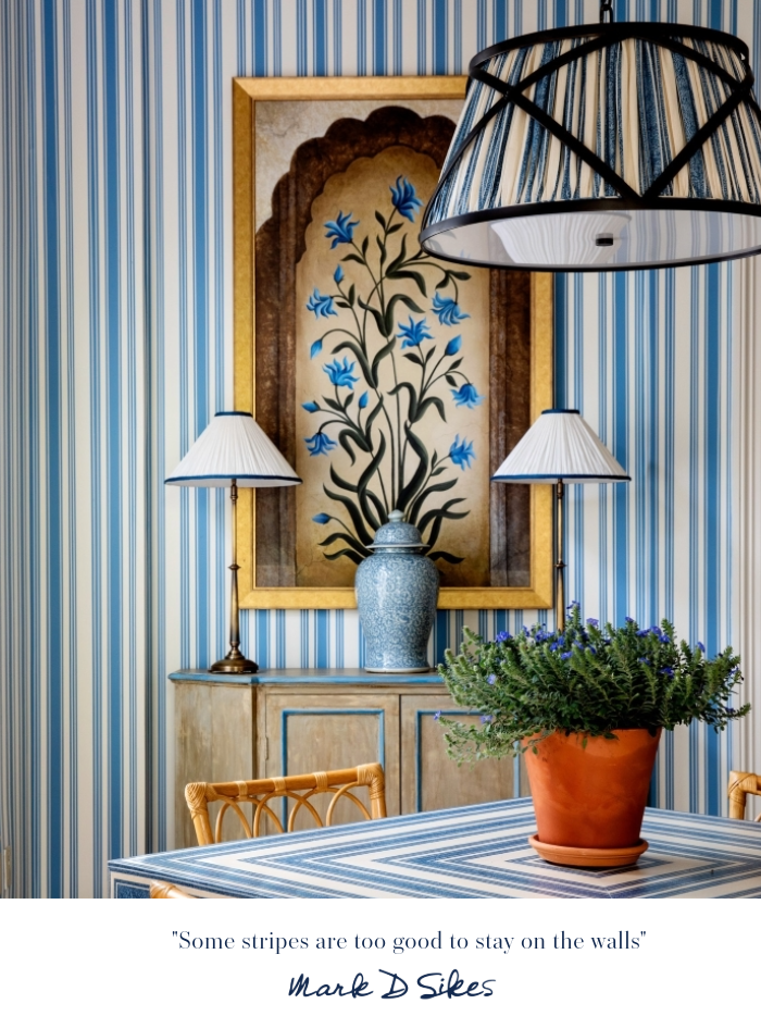 A blue and white striped dining room featuring striped wallpaper, a matching patterned table, botanical art, and pendant light.