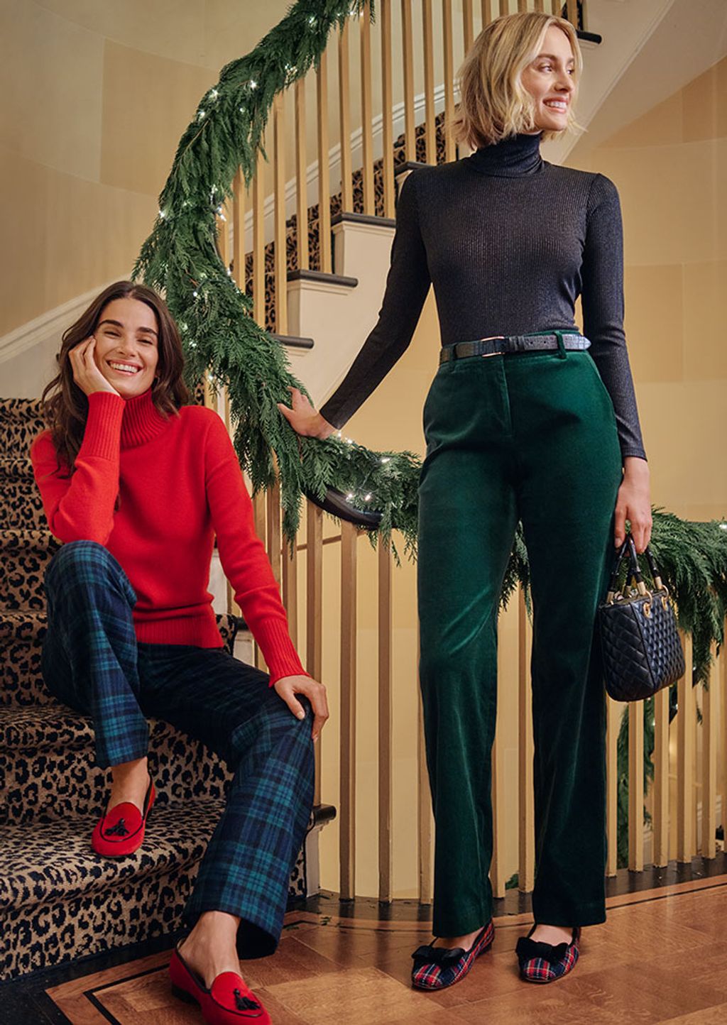 Two women in festive clothing standing by a staircase.