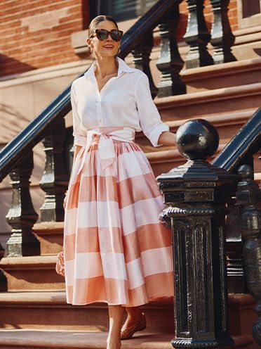 Woman in pink and white gingham skirt and white button down blouse. 