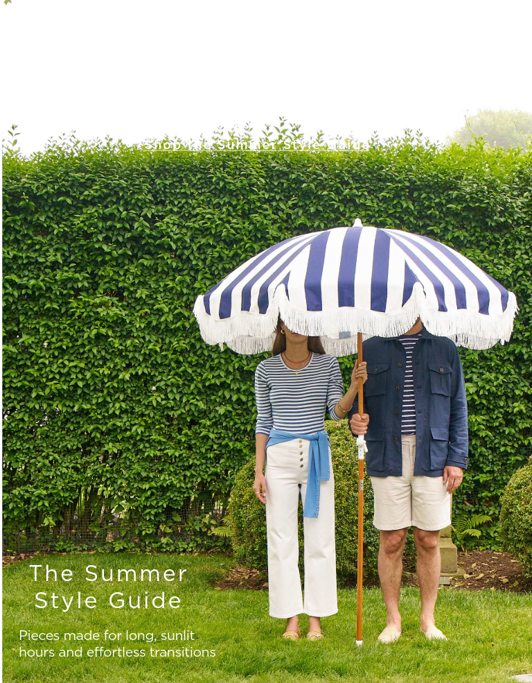 man and woman standing outside in navy and white outfits holding a blue and white stripe umbrella