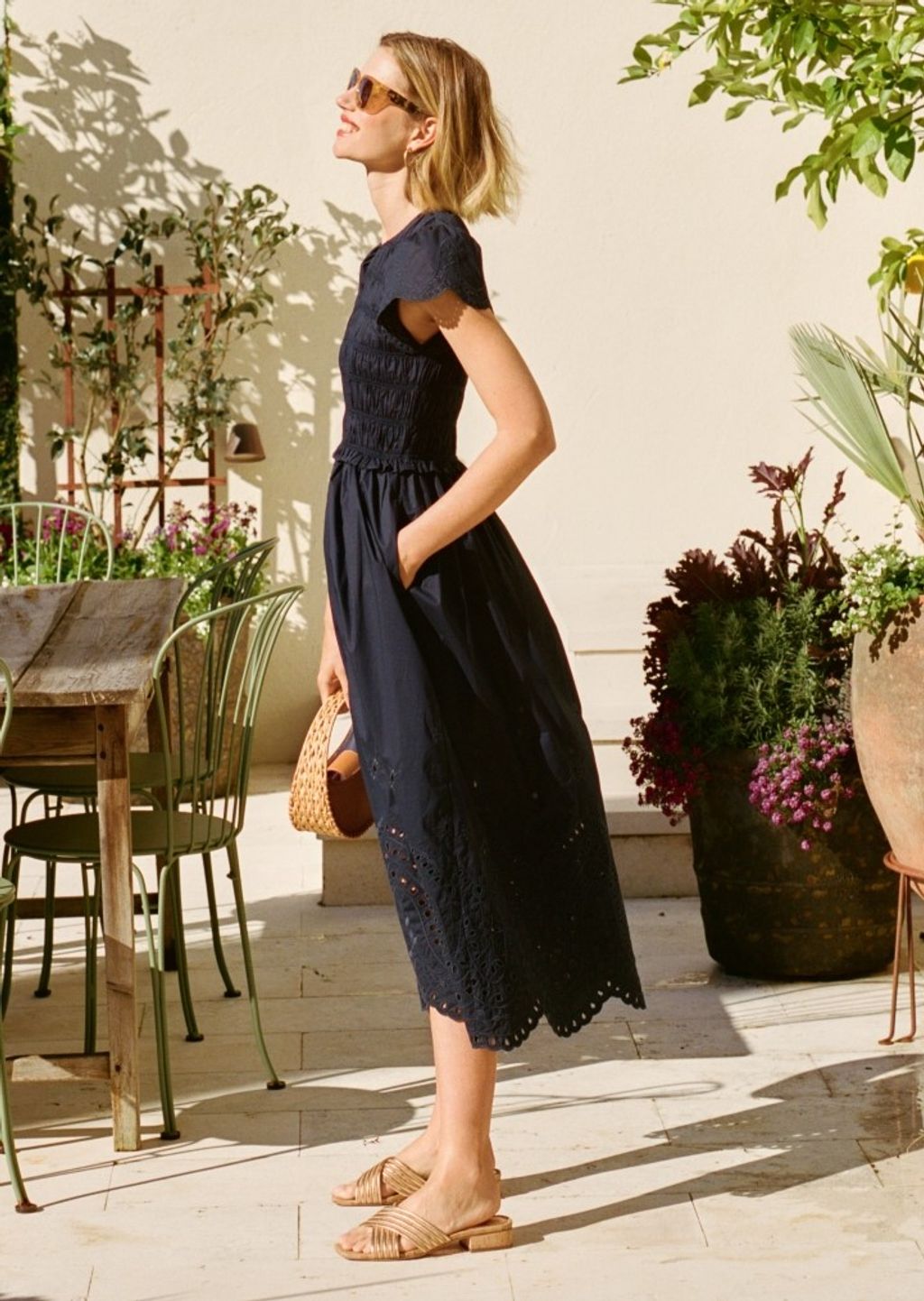 woman standing outside wearing a navy midi dress with eyelet trim and smocking