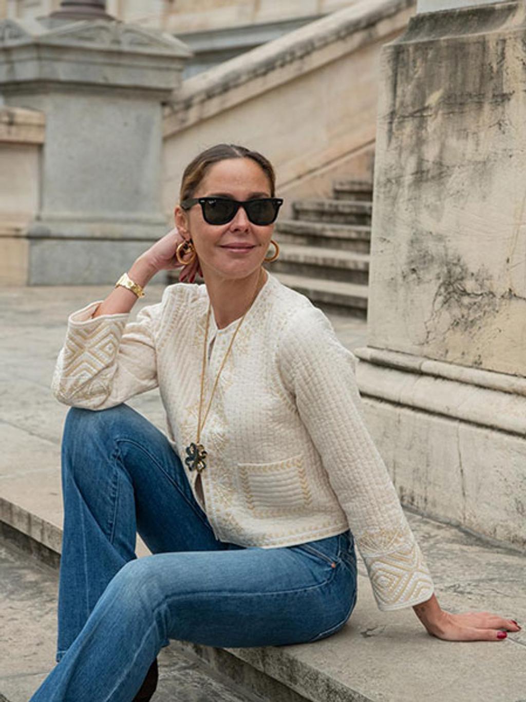 Filipa de Abreu sitting on stairs in a sweater, jeans, and sunglasses