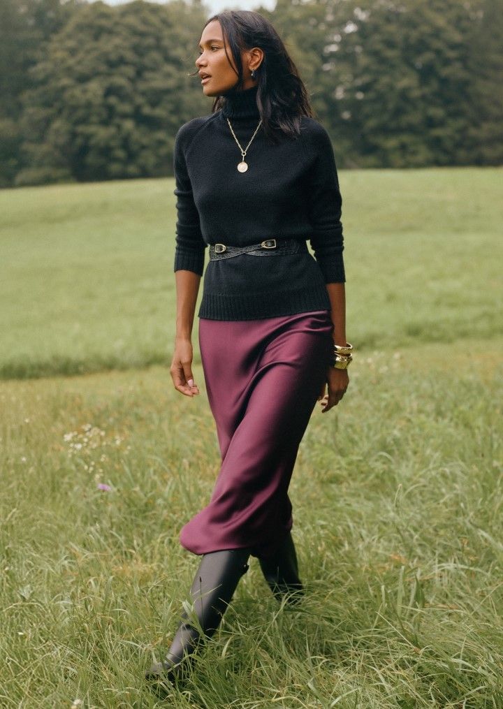 woman walking outside in field wearing black cashmere turtleneck sweater with merlot silky pencil skirt