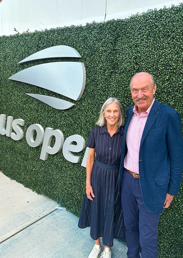 Couple posing in front of US OPEN greenery and logo