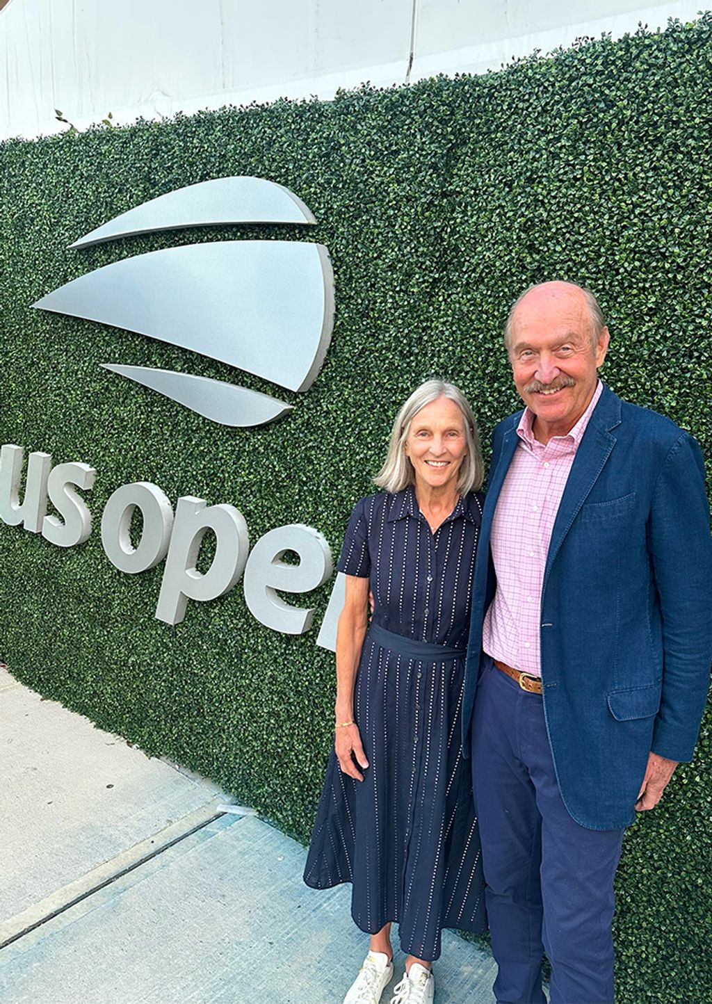Couple posing in front of US OPEN greenery and logo