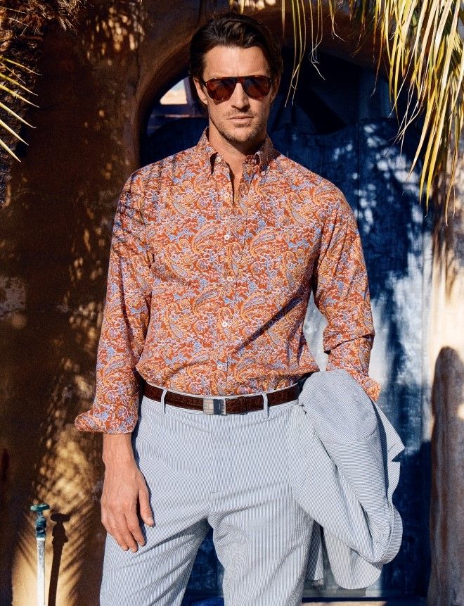man standing outside wearing a multicolor floral shirt and seersucker pants