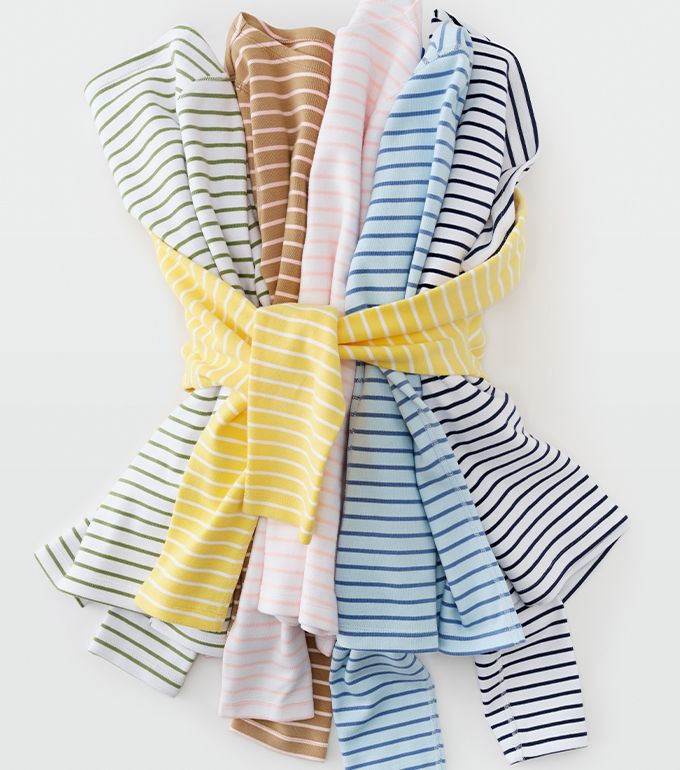 woman standing outside wearing pink and white stripe cinch waist button down shirt with a brown paisley swirl silky skirt and wide brim hat