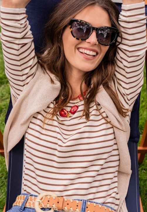 close up image of woman seated wearing brown and cream striped top
