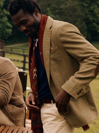 man turned to the side, standing outside wearing brown and olive herringbone tweed sportcoat