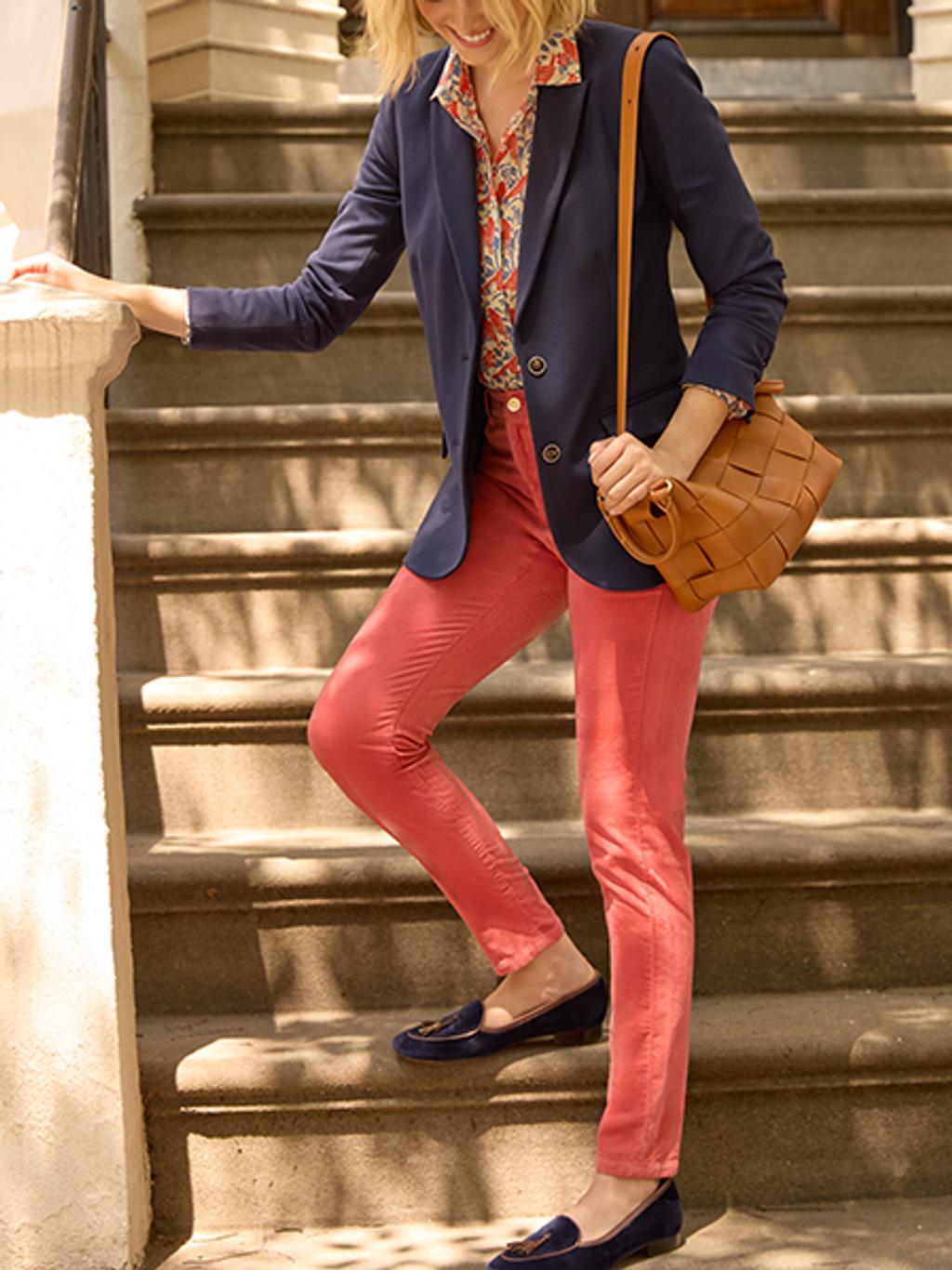 Model carrying woven leather tote and wearing navy blazer, velveteen pants, and printed button-down.