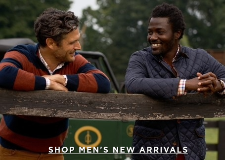 two men outside leaning over a fence, one wearing burgundy and navy stripe knit the other wearing a navy quilted jacket