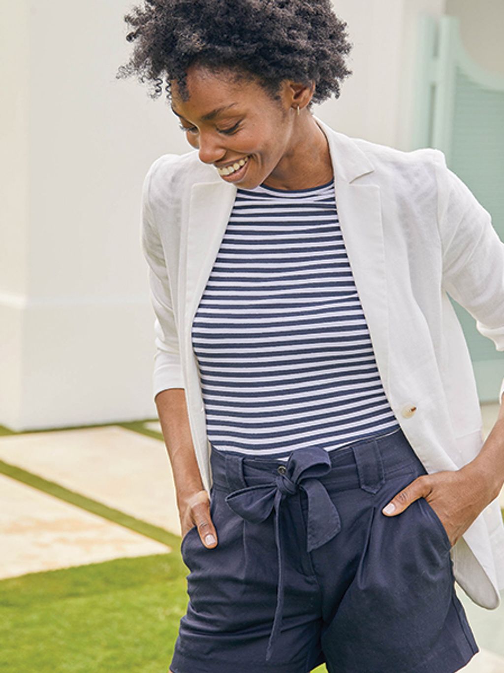 Model in white blazer, striped tee, and shorts