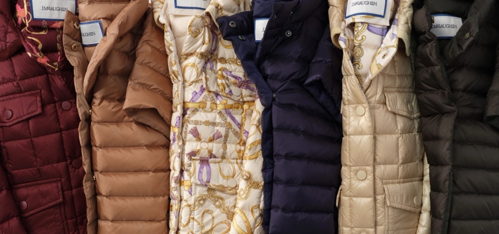 Six quilted puffer jackets in a row, in various colors and one patterned.