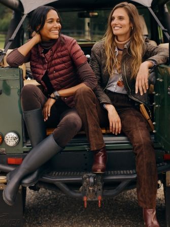 two women seated on back of truck in puffer jackets