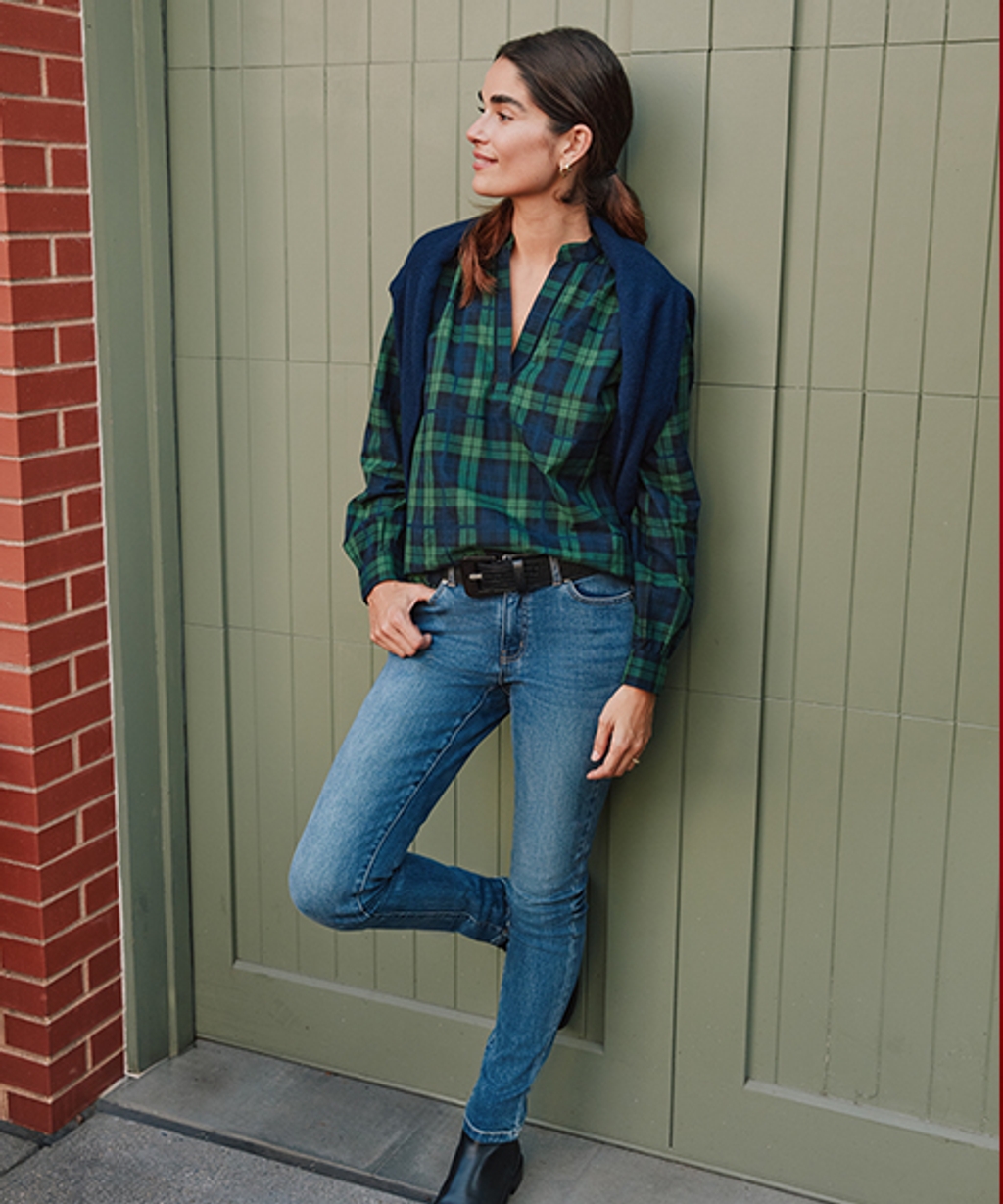 Model wearing tartan button-down, slim fit jeans, leather boots, leather belt, and cashmere turtleneck.