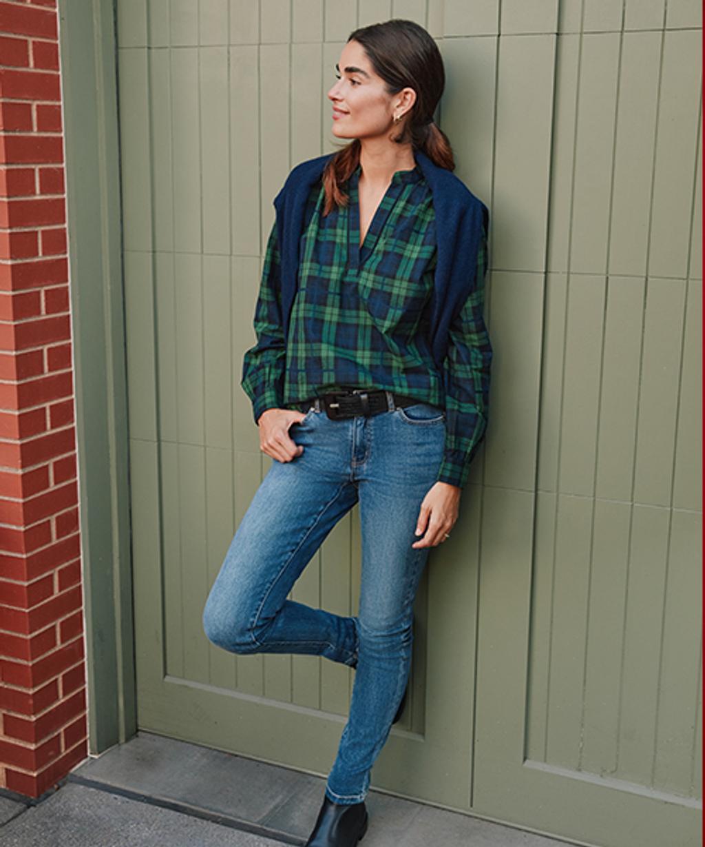 Model wearing tartan button-down, slim fit jeans, leather boots, leather belt, and cashmere turtleneck.