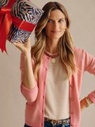 woman wearing pink cashmere cardigan sweater and holding zebra wrapped gift box with red box