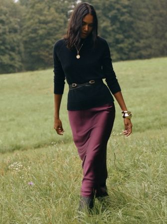 woman outside in grass wearing silky burgundy skirt and black turtleneck