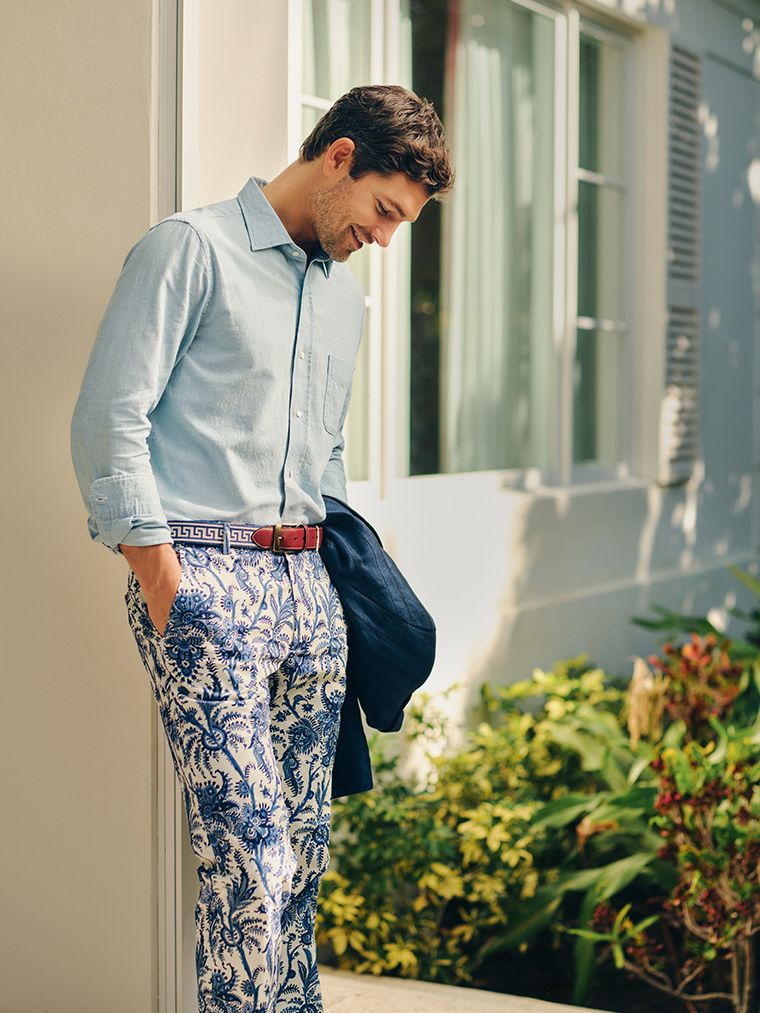 man standing outside in toile printed pants and blue button down shirt. 