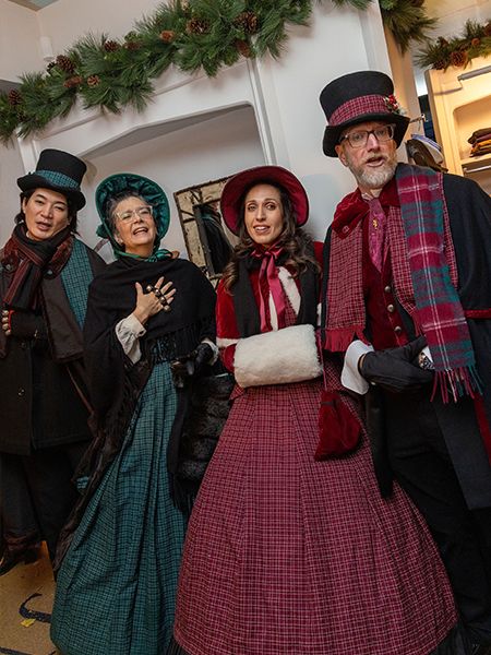 Four Christmas carolers posing for a photo.