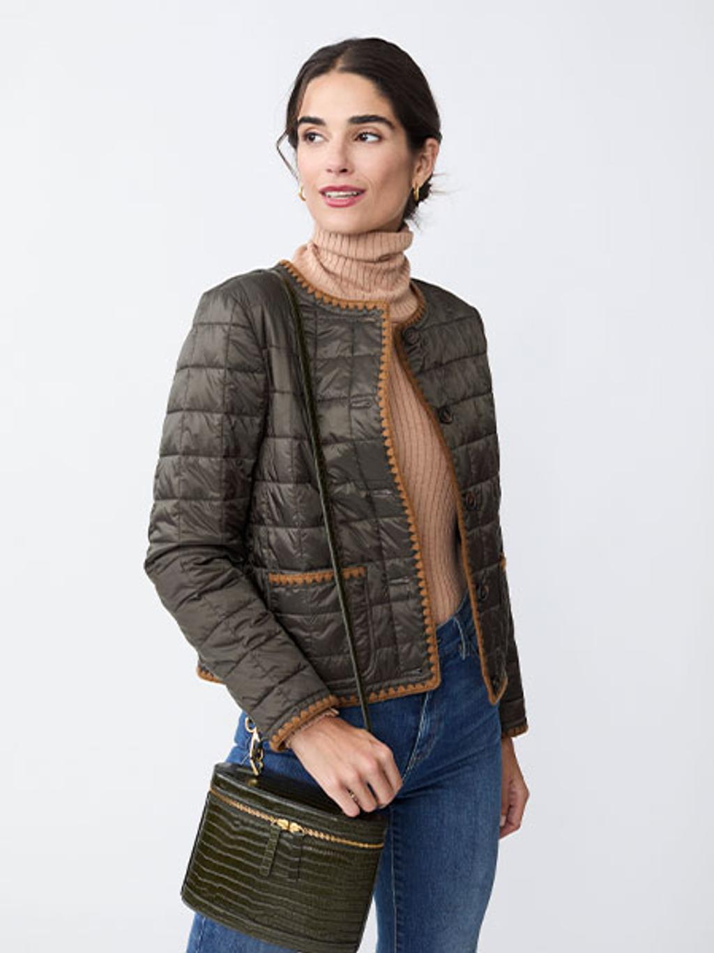 Model in camel turtleneck, green quilted jacket, and jeans