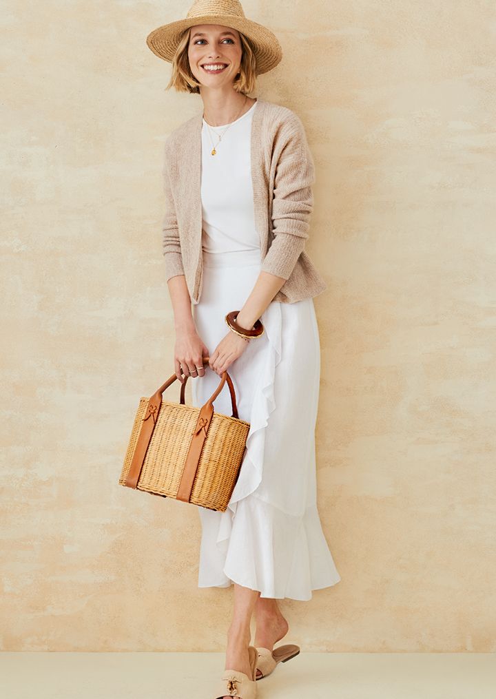 Woman posing in a linen white skirt and oatmeal colored cardigan. 