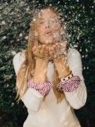 woman wearing off white cashmere turtleneck and blowing a kiss with snow