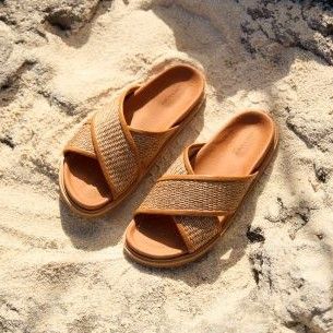 pair of tan criss cross leather and raffia sandals on beach