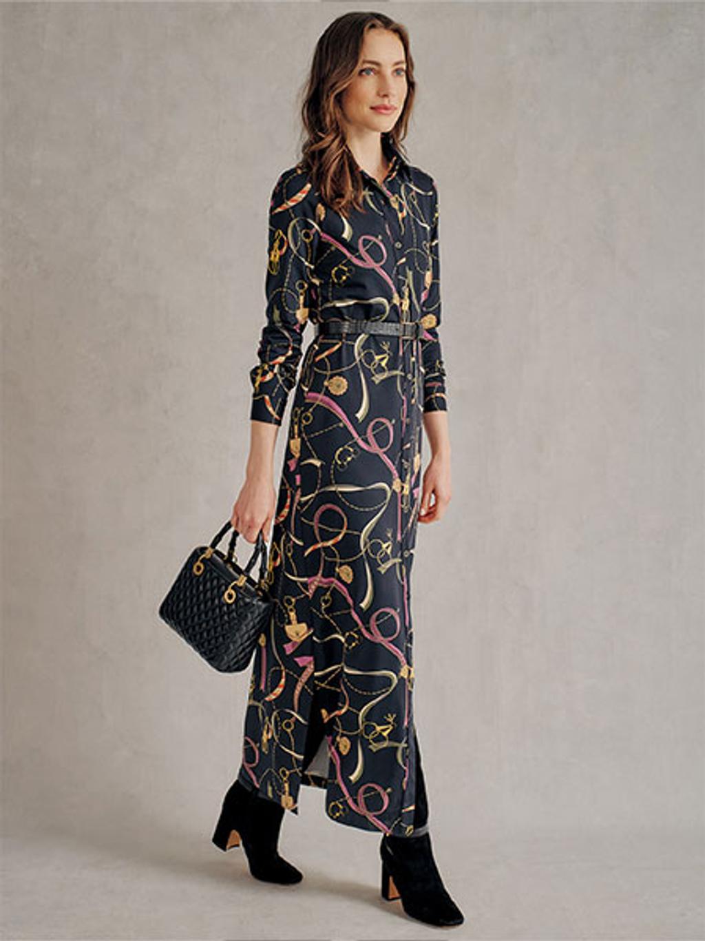 Women wearing a long printed wrap dress with black heels carrying a black handbag.
