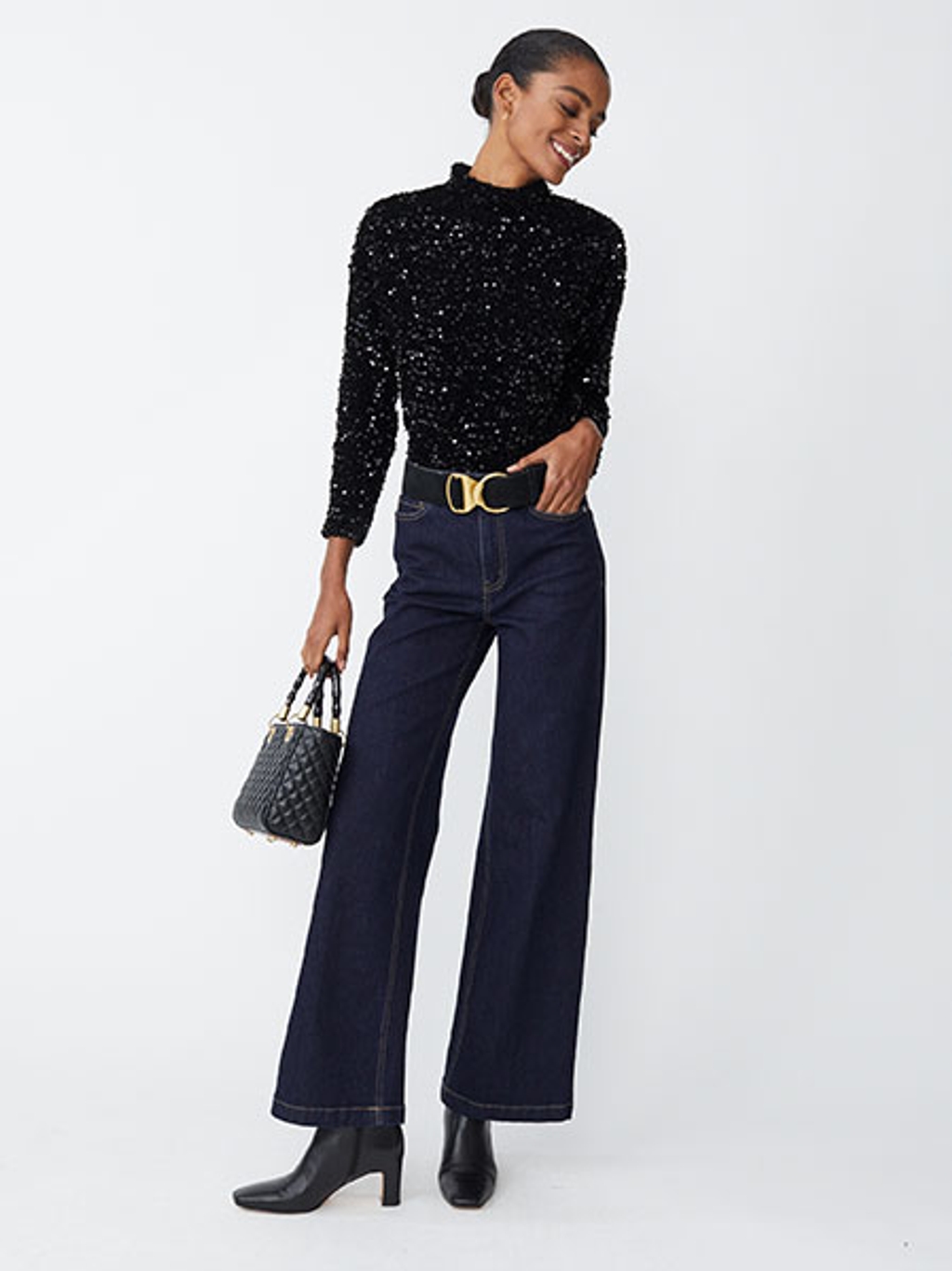 Model with black sequined top, jeans, and boots