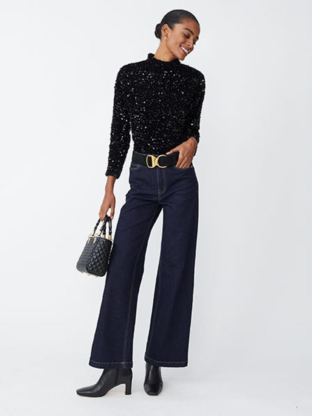 Model with black sequined top, jeans, and boots