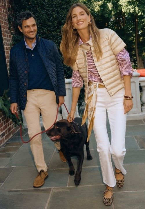 couple walking with dog, her wearing gold puffer with white jeans and striped shirt