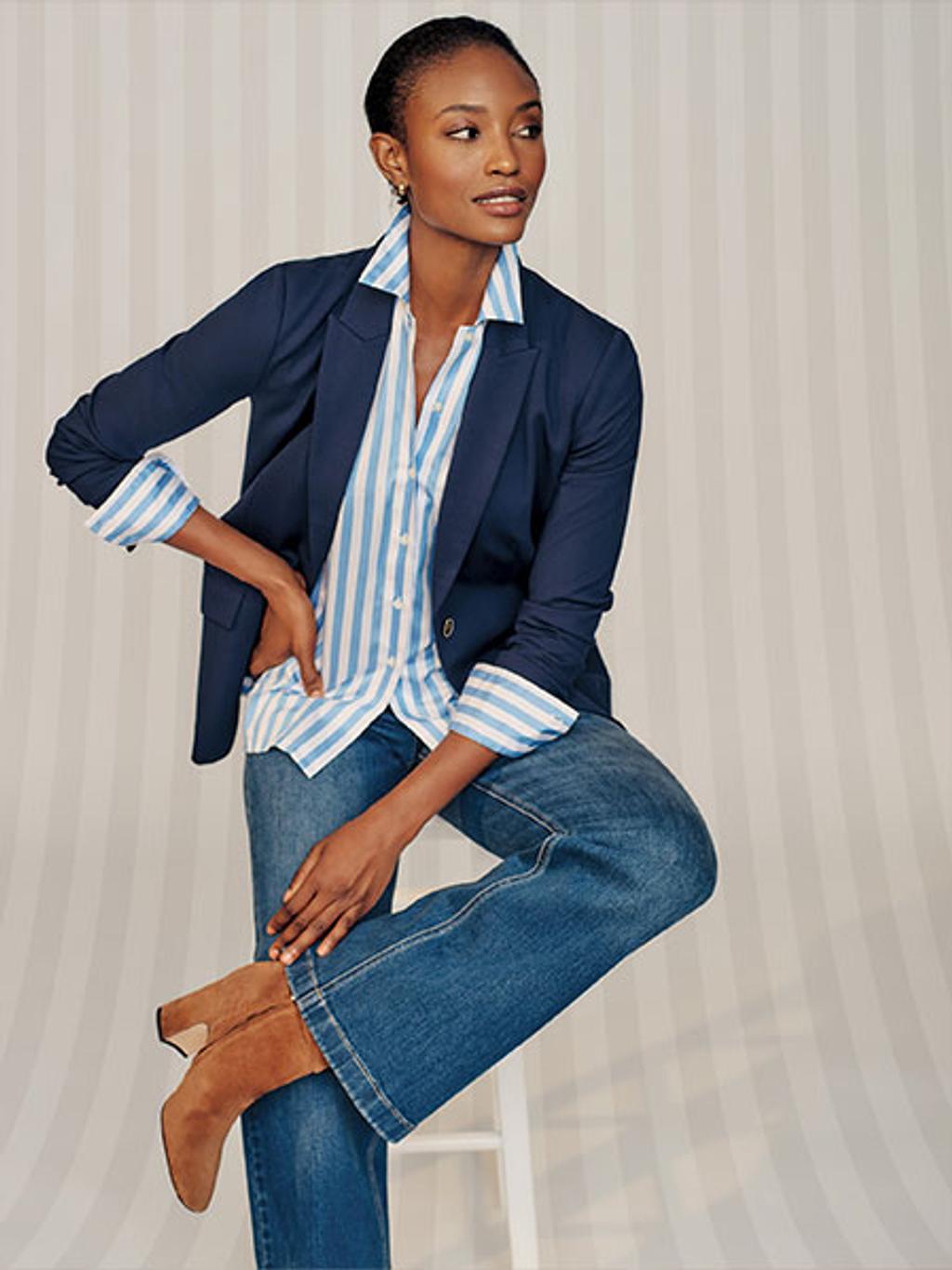 Women wearing a navy blazer and white and blue button up with blue denim jeans and boots. 