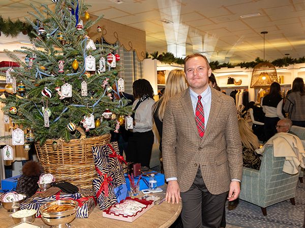 Man dressed in formal attire posing beside holiday table setting.