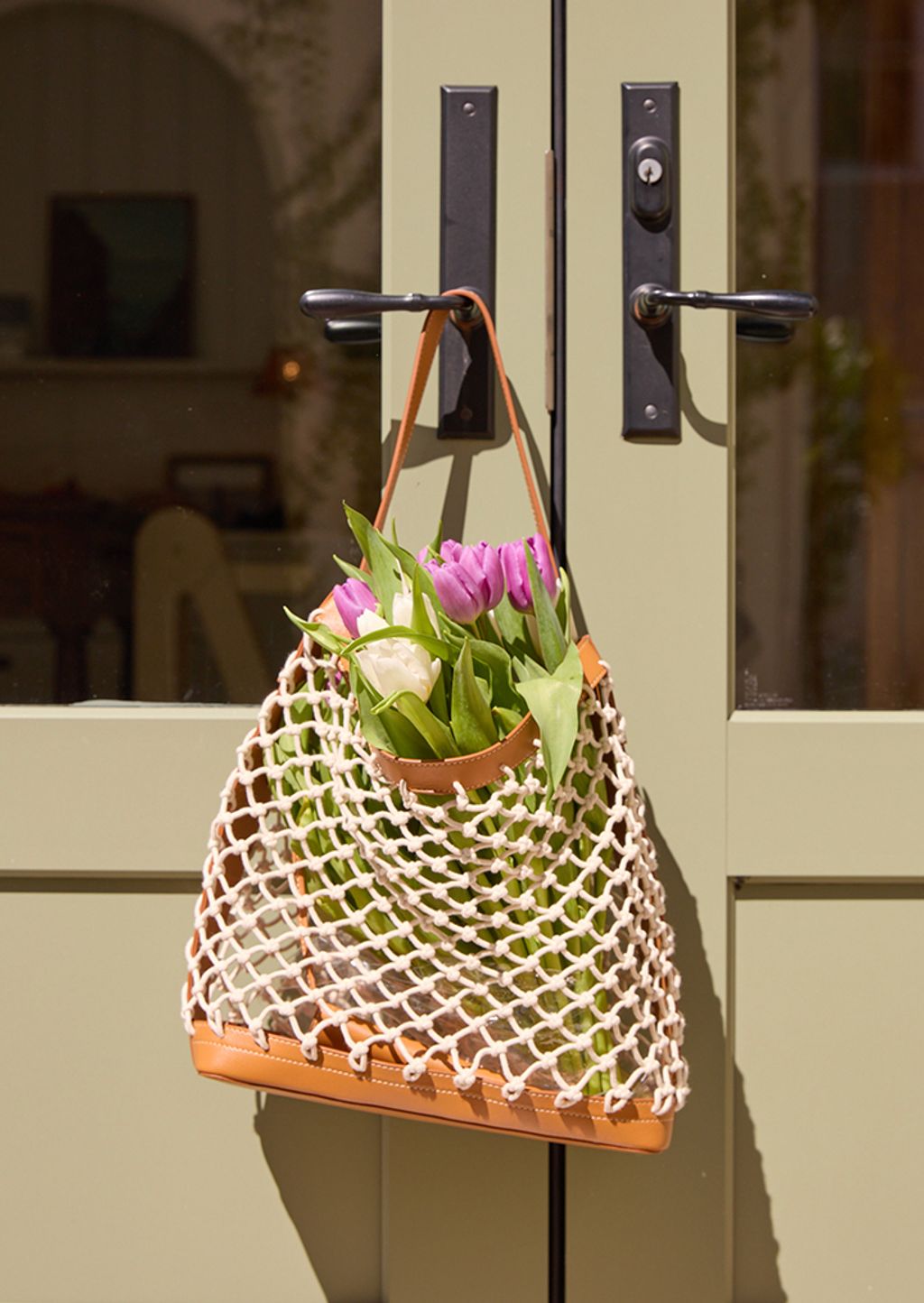 open knit handbag holding a bouquet of tulips.