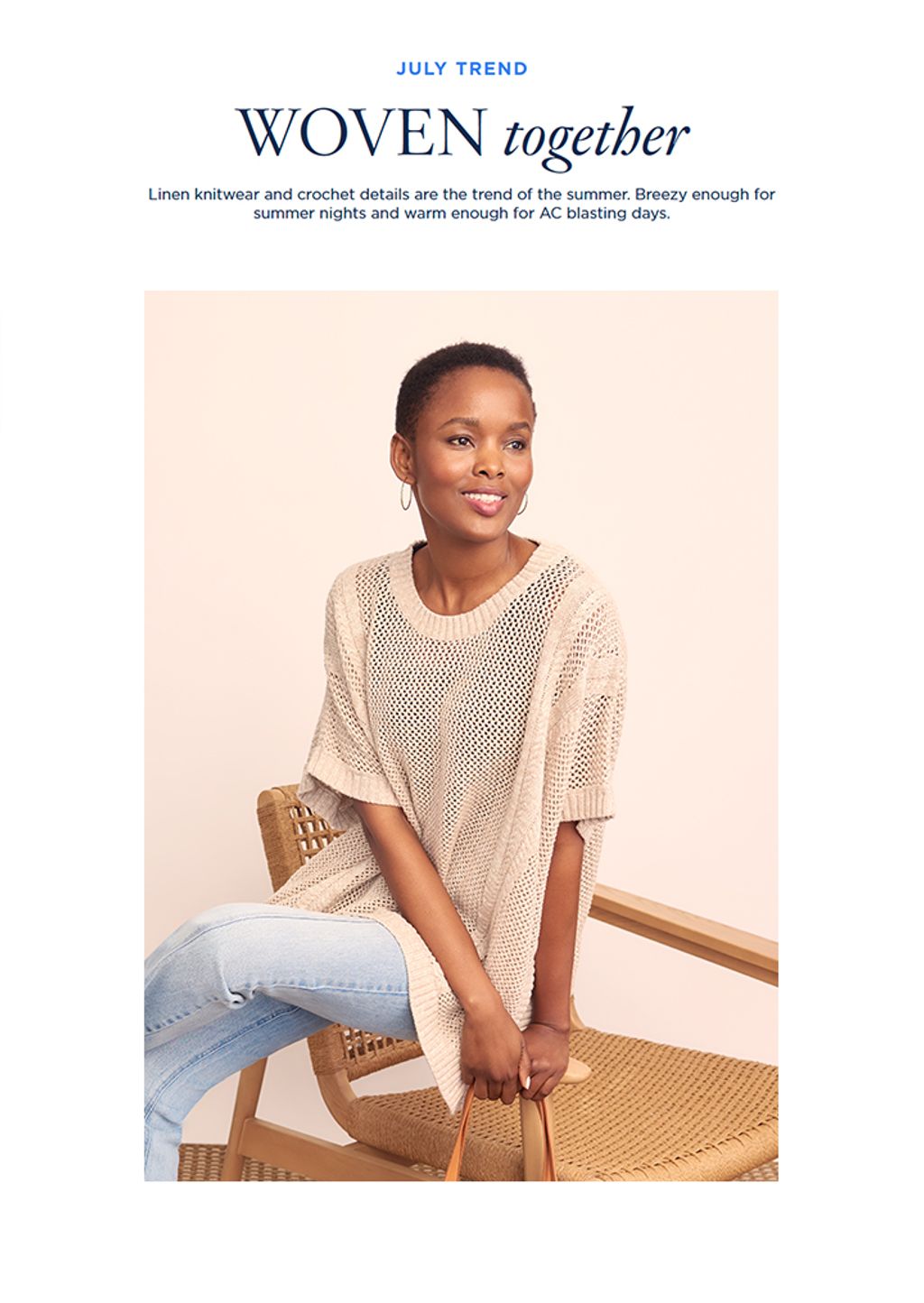 Model seated in beige poncho and blue jeans.
