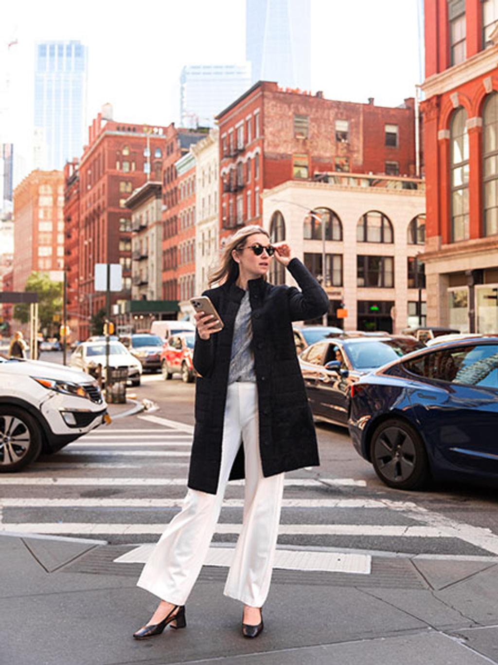 Model wearing Tripp cardi-coat in black, gray sweater, and white pants 