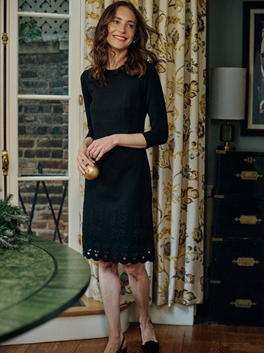 Model wearing a mid length back dress and heels.