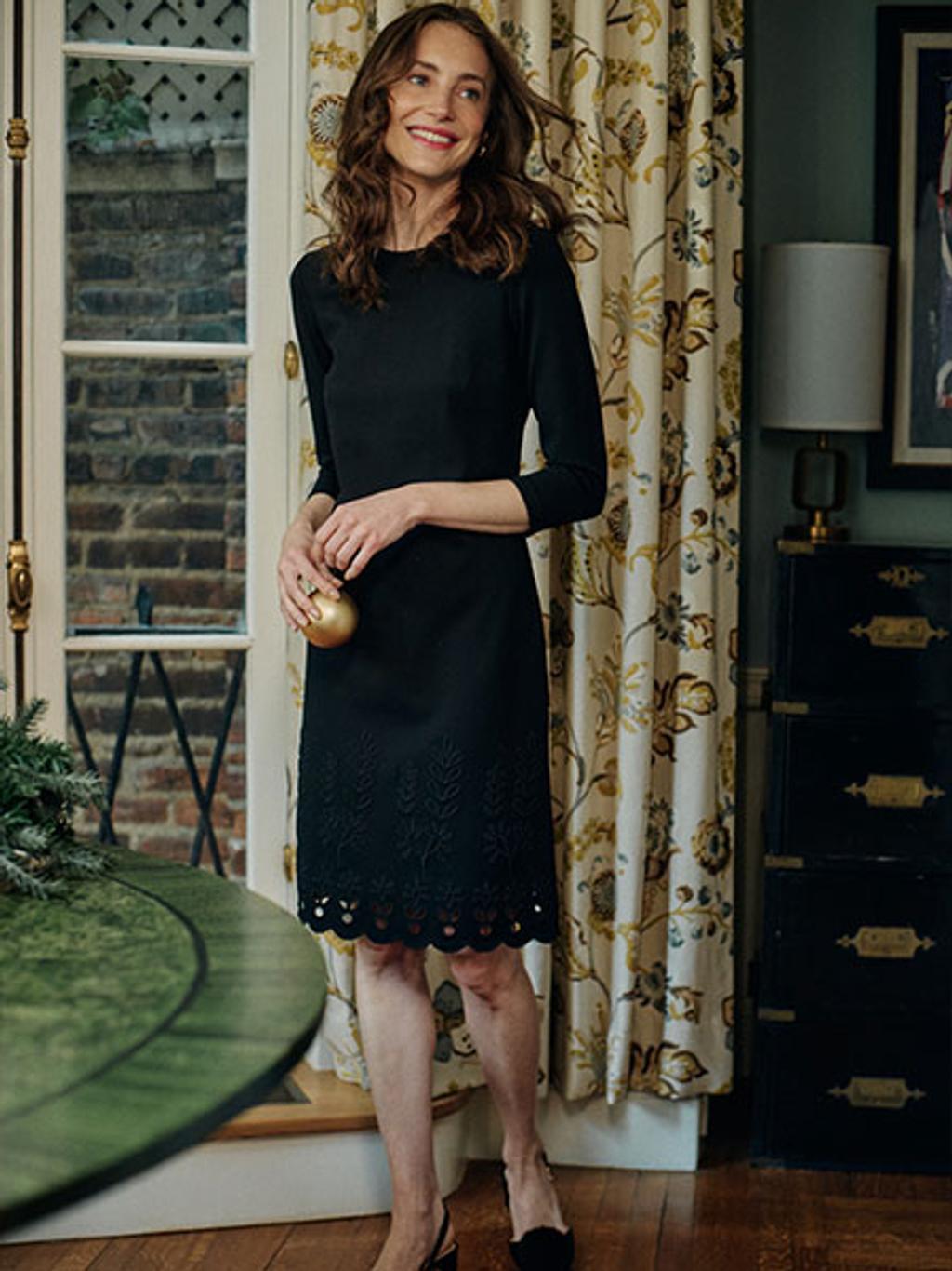 Model wearing a mid length back dress and heels.