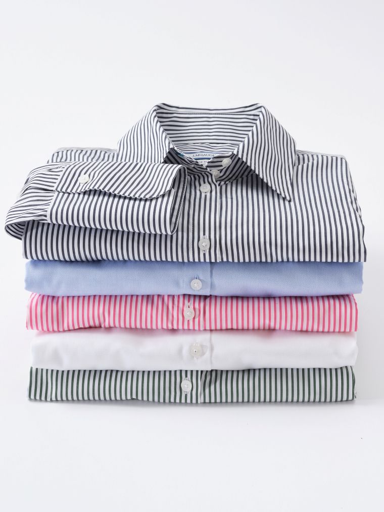 A stack of five neatly folded dress shirts: navy striped, light blue, pink striped, white, and green striped.