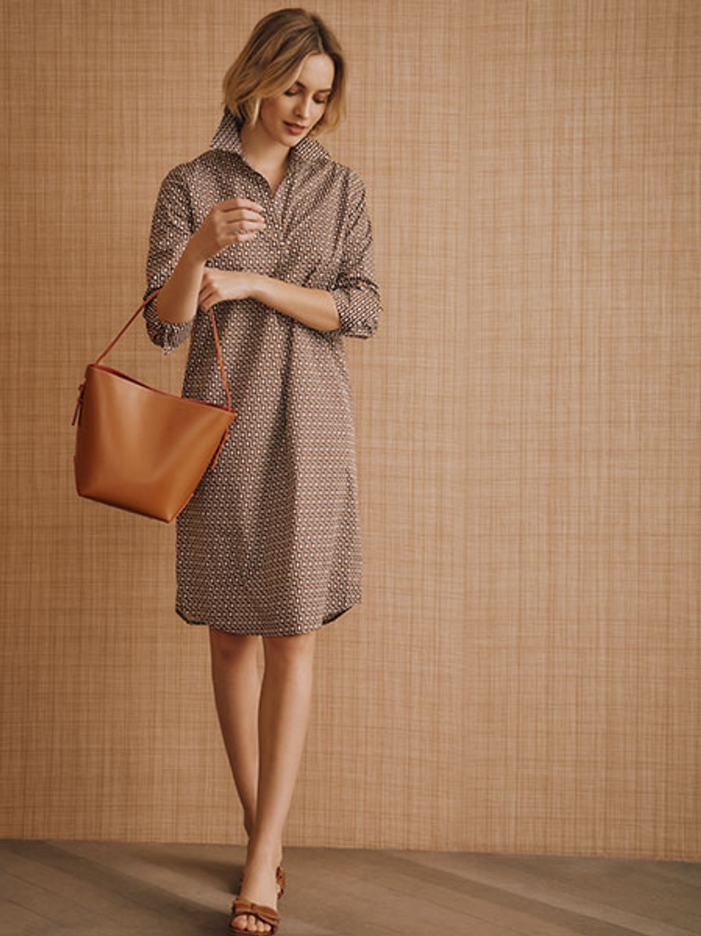 Model in blue striped shirt and white pants Model wearing a patterned brown dress holding a brown leather handbag