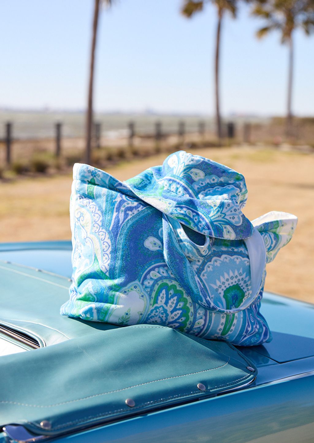 Matching terrycloth tote and hat sitting on a hood of a car 