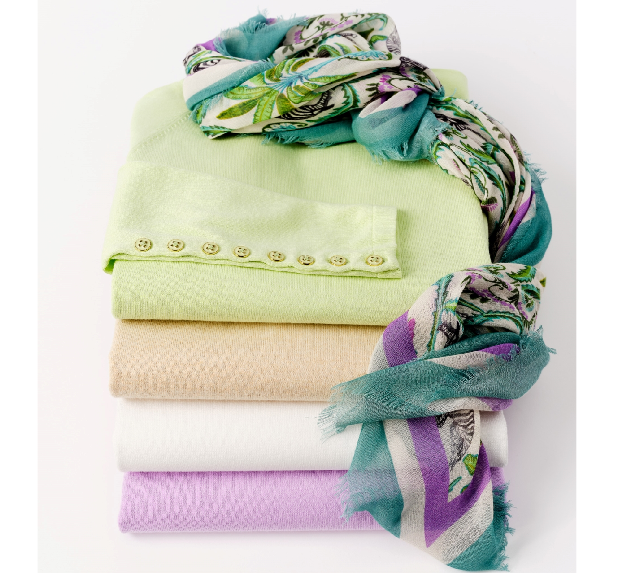 stack of womens sweaters in various colors with button cuff detail spotlighted