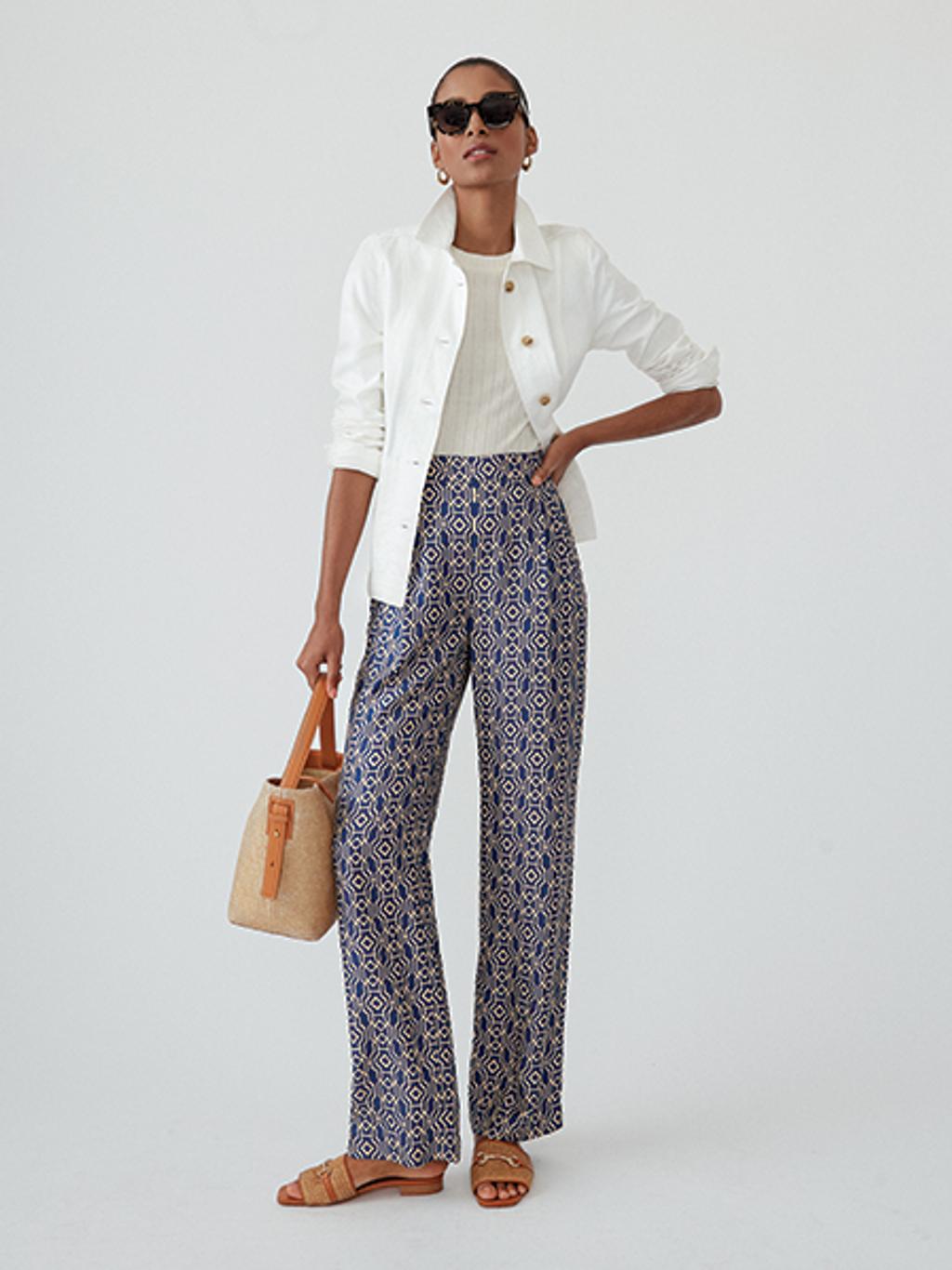 Model wearing printed pants, jacket, and sandals