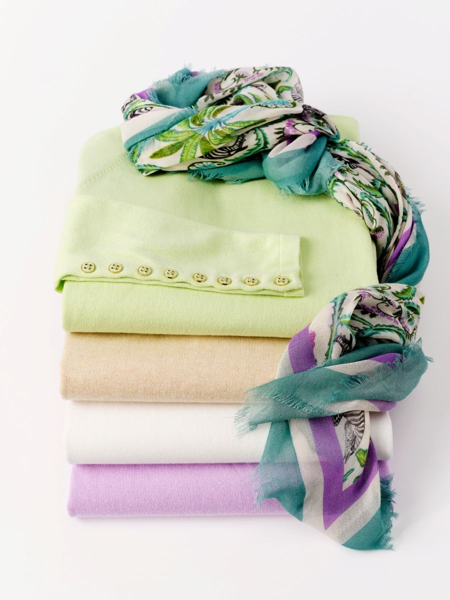 stack of womens spring palette sweaters with printed paisley scarf at the top