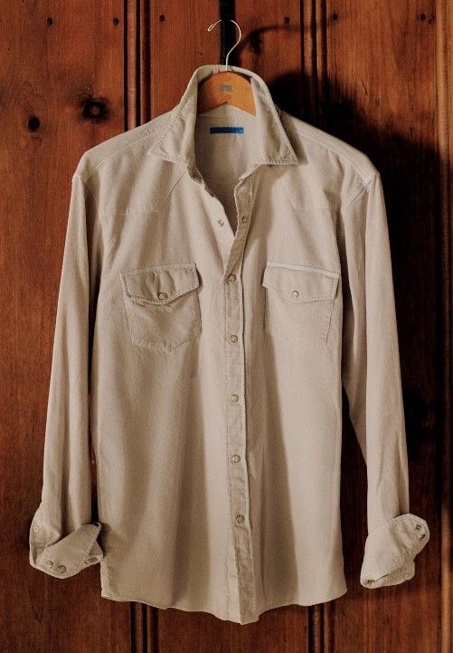 men corduroy button down shirt in light beieg hanging in front of a wooden door