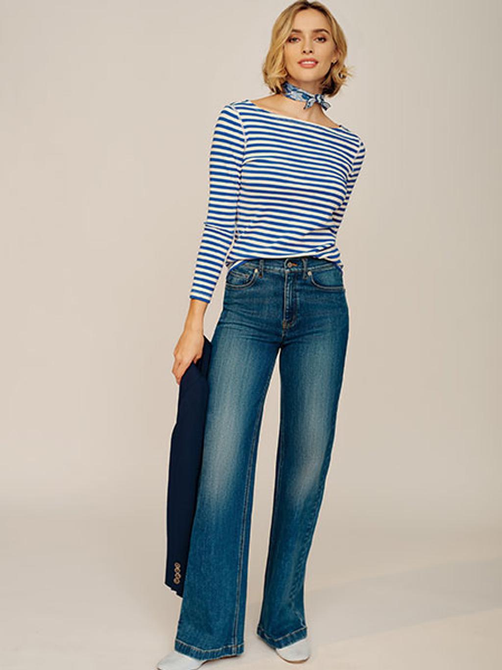Women with short blonde hair wearing a blue and white striped shirt and blue denim jeans.