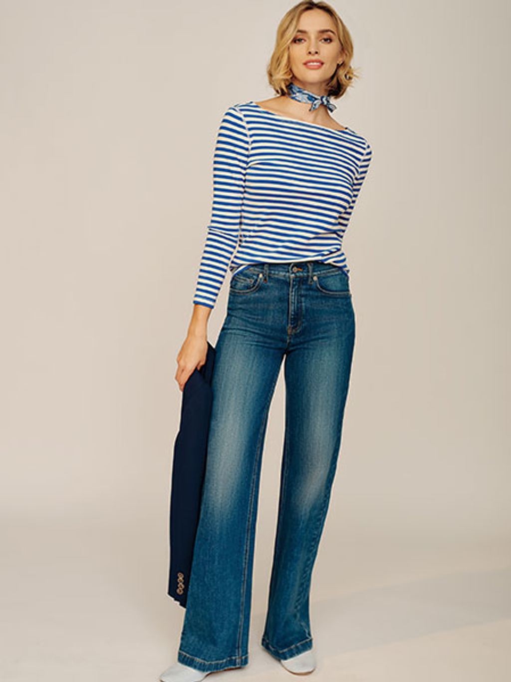 Women with short blonde hair wearing a blue and white striped shirt and blue denim jeans.
