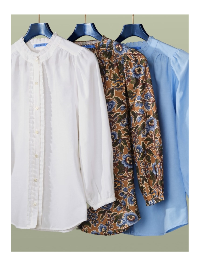 group of womens puff sleeve ruffle placket blouses in various colors and one print hanging on a rack